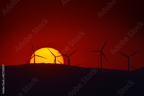 beautiful sunset with wind turbines silhouettes on the hill in s