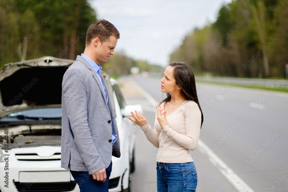 Couple near broken car on a highway roadside Couple near broken car on a highway roadside