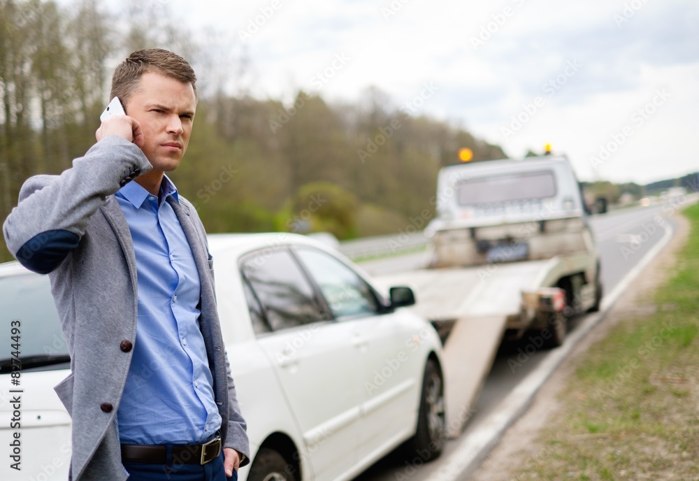 Man calling while tow truck picking up his broken car Man calling while tow truck picking up his broken car