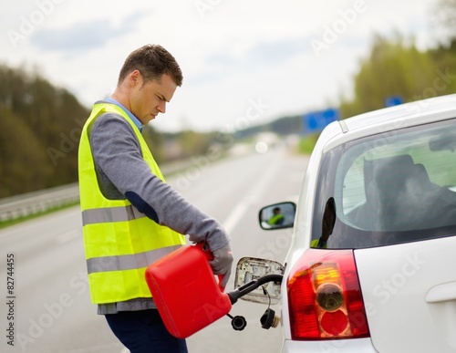 Man refuelling her car on a highway roadside photo