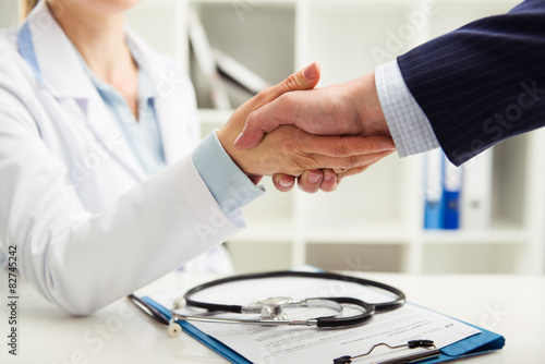 Woman doctor shaking hand with businessman in the office