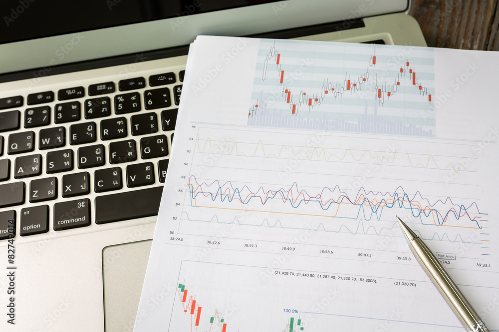 Financial charts on the table with laptop Financial charts on the table with laptop