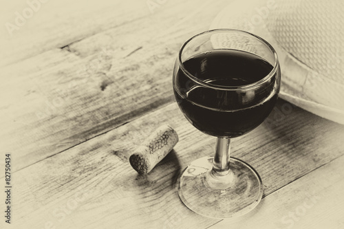 red wine glass and old book on wooden table. vintage filtered photo