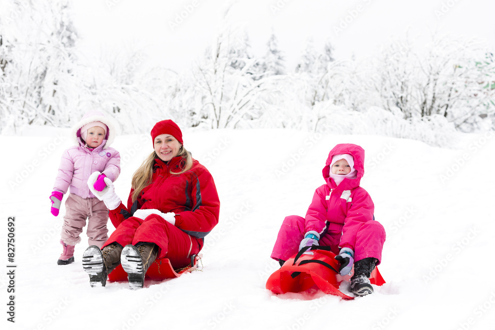 mother and her little daughters with bobs in snow mother and her little daughters with bobs in snow