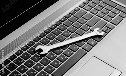 electronic technical support concept - spanners on computer