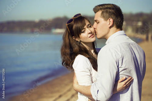 Cheerful couple embracing and posing on the beach on a sunny day