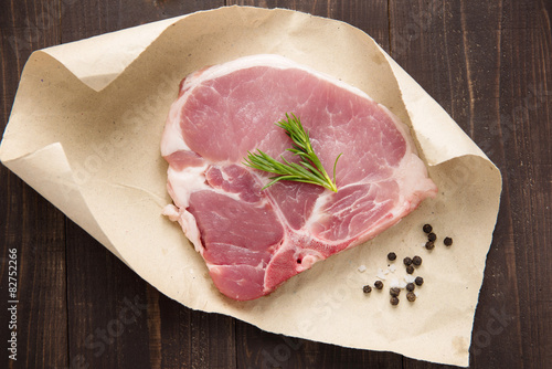 raw pork chop steak on paper and wooden background