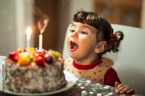 little girl blows out the candles on the cake