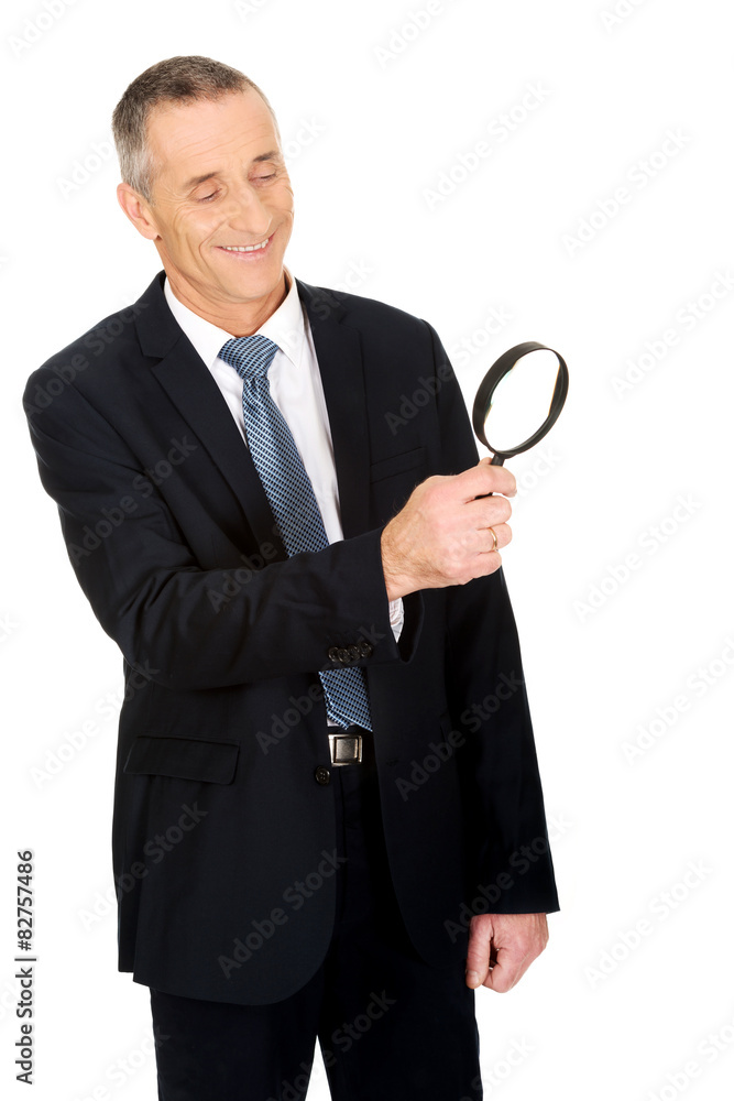 Businessman looking through a magnifying glass Businessman looking through a magnifying glass