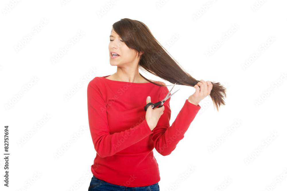 Fototapeta premium Depressed woman cutting her hair.