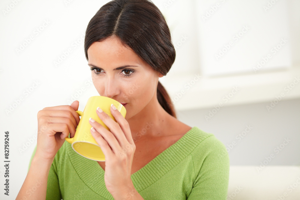 Young female drinking from a yellow mug Young female drinking from a yellow mug