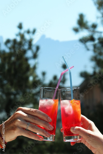 two women's hands holding cocktails saying cheers