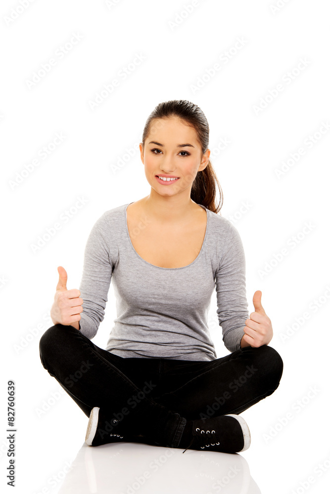 Woman sitting cross legged with thumbs up. Woman sitting cross legged with thumbs up.