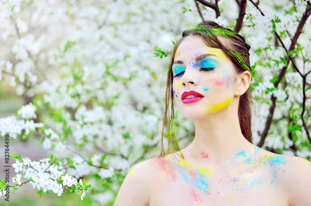 Beautiful woman with colored paint on face outdoor