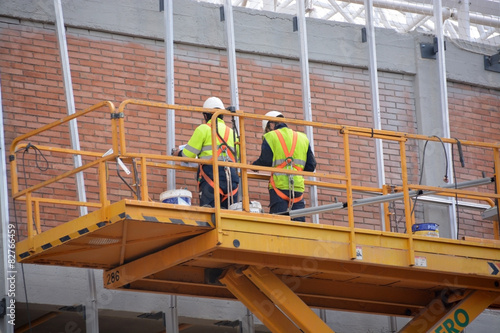 obreros trabajando encima de un andamio