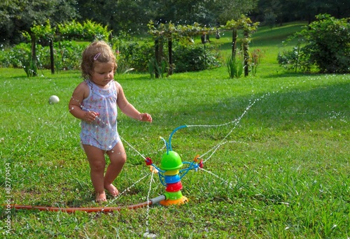 Little girl playing with toy sprinkler