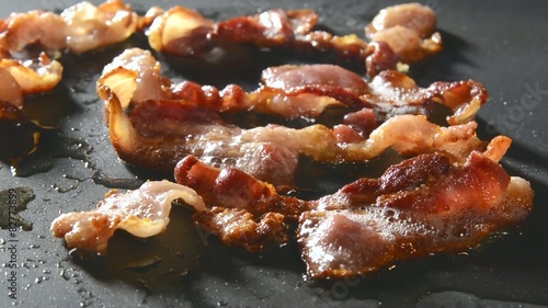 Closeup of bacon strips frying on a grill
