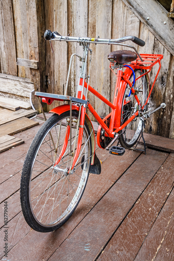 Vintage red bike against the old wooden home, Thailand.