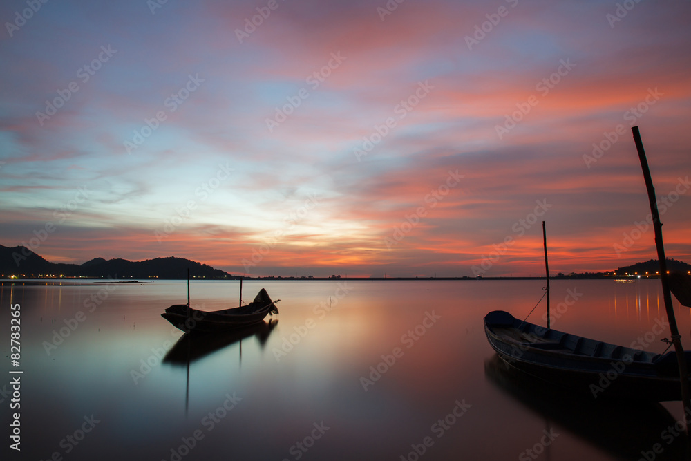 Beautiful silhouette fishing boat in lake at sunset sky.
