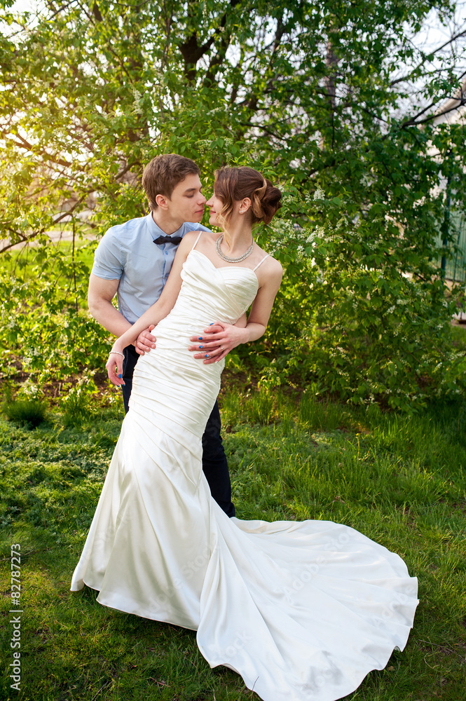 Bride and groom stand near a flowering tree in spring garden Bride and groom stand near a flowering tree in spring garden