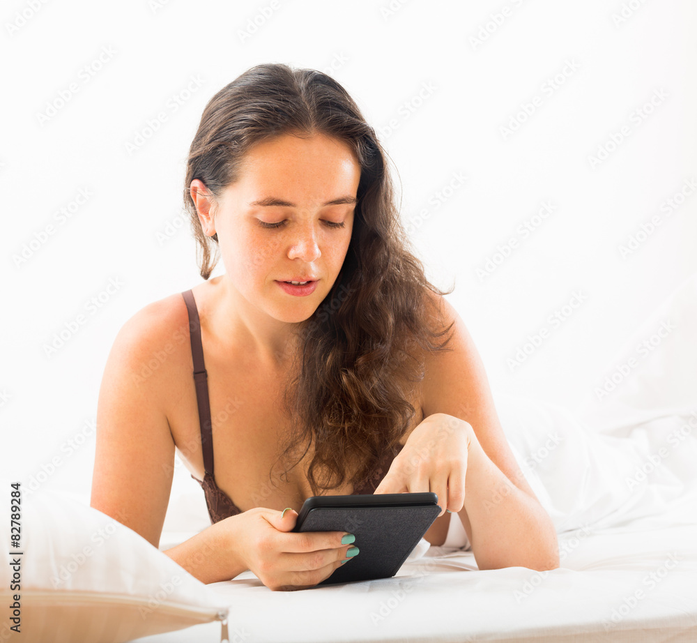 Fototapeta premium Woman with ereader lying in bed