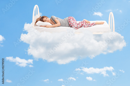 Woman sleeping on a comfortable bed in the clouds photo