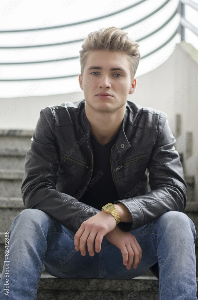 Blond young man sitting on stairs outside Blond young man sitting on stairs outside