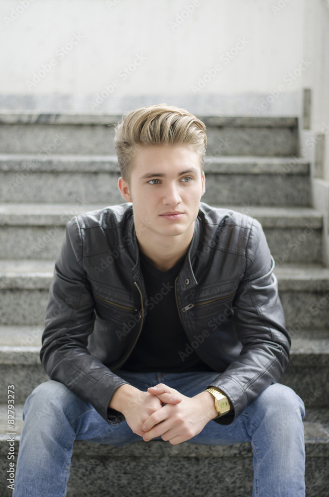 Blond young man sitting on stairs outside Blond young man sitting on stairs outside