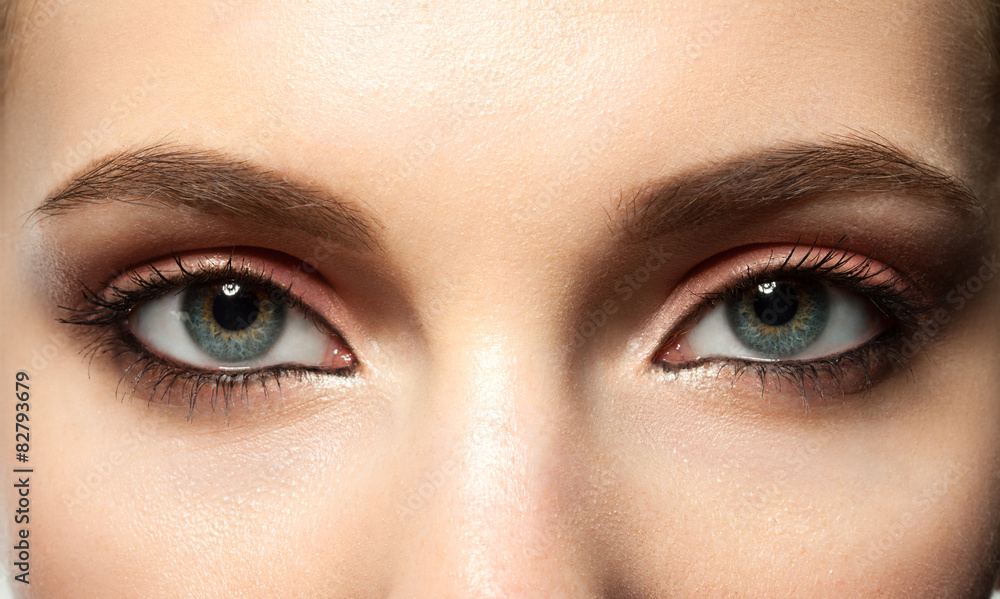 Naklejka premium kobiece niebieskie oko z makijażem z brązowymi brwiami i czarnymi rzęsami