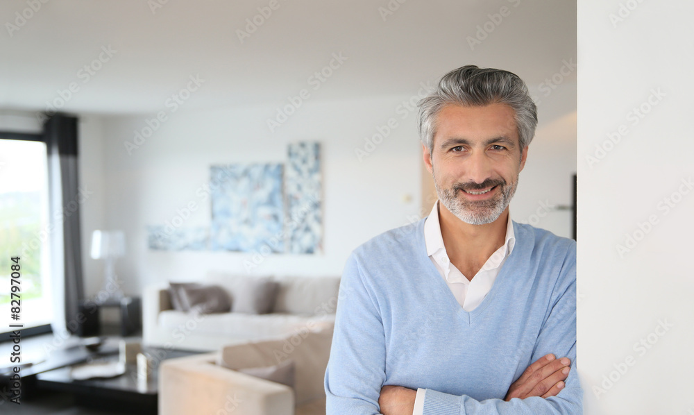 Smiling mature man standing in contemporary house Smiling mature man standing in contemporary house