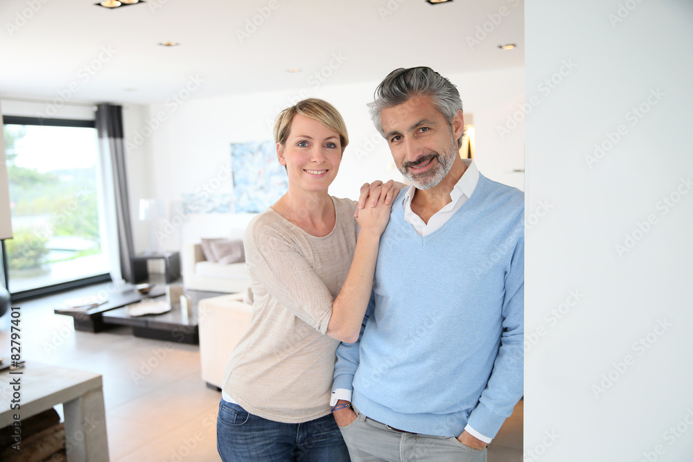 Obraz premium Smiling middle-aged couple standing in brand new home