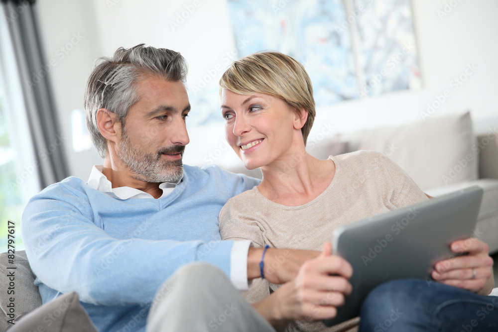 Middle-aged couple websurfing on internet with touchpad Middle-aged couple websurfing on internet with touchpad