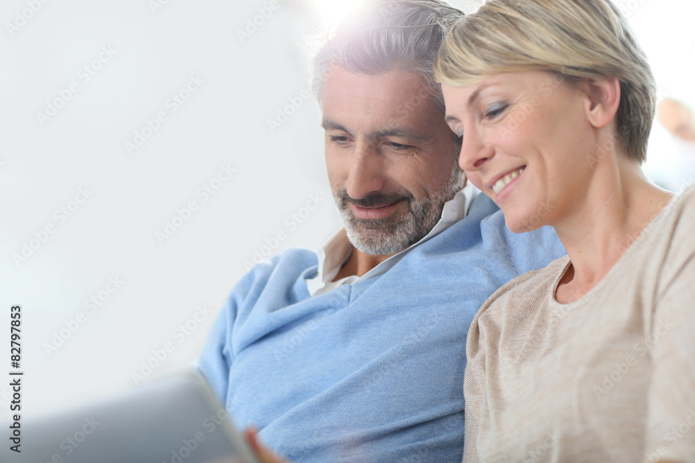 Middle-aged couple websurfing on internet with touchpad Middle-aged couple websurfing on internet with touchpad