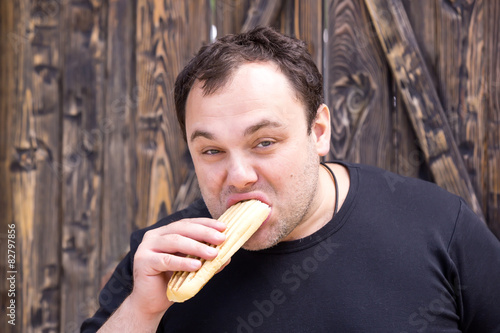 brutal young man eating a hot dog