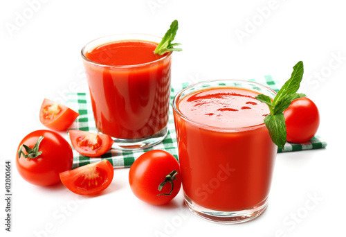 Glasses of fresh tomato juice on checkered napkin, isolated on white