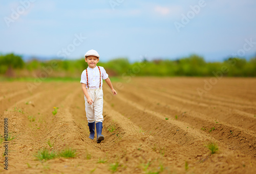 cute little farmer walking on spring field