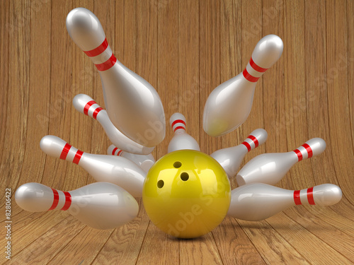 Yellow bowling ball and scattered skittles on wood