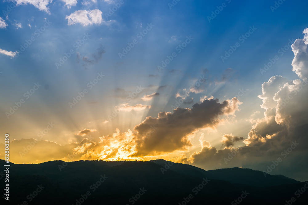 Sunset behind mountain with beautiful sunbeam through the cloud Sunset behind mountain with beautiful sunbeam through the cloud
