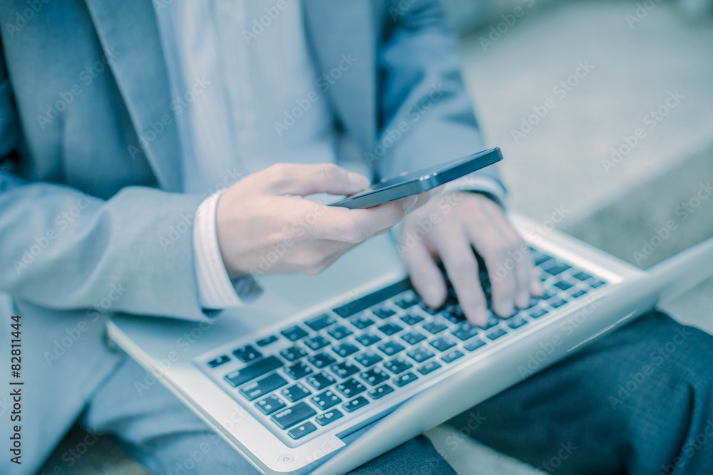 Businessman using laptop pc and mobile phone. He is sitting on a Businessman using laptop pc and mobile phone. He is sitting on a