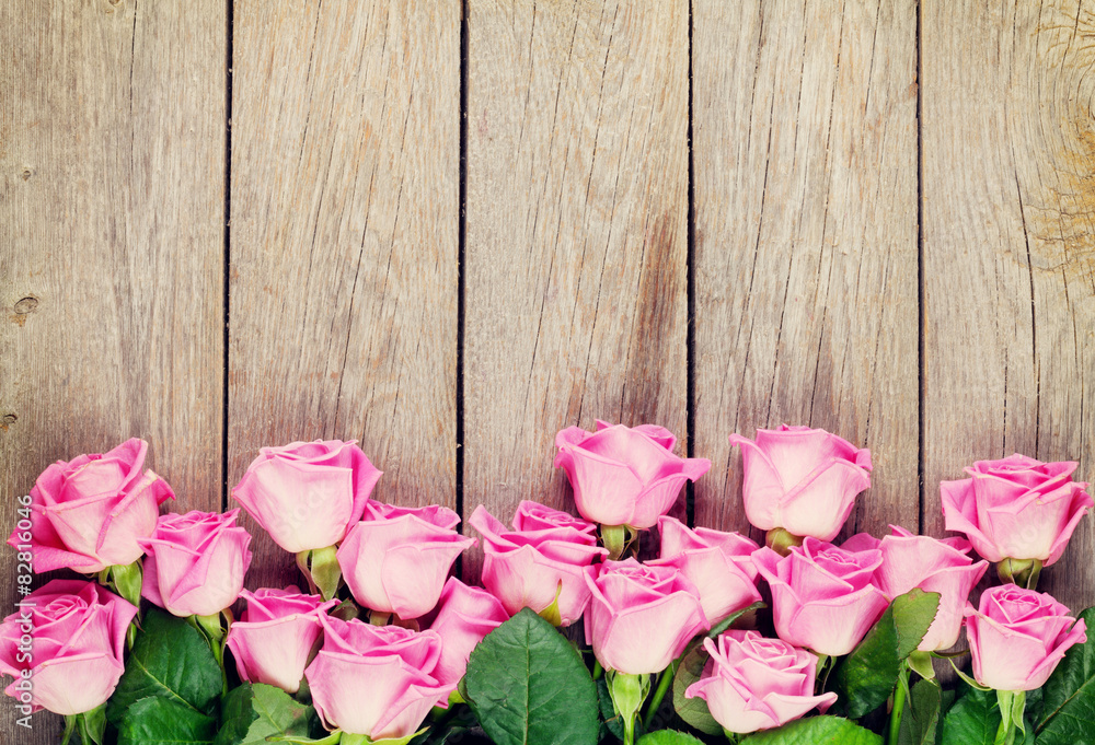 Fototapeta premium Pink roses bouquet over wooden table