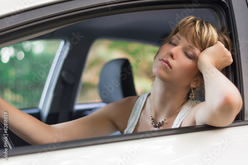 Attractive blonde young woman sleeping in a car 