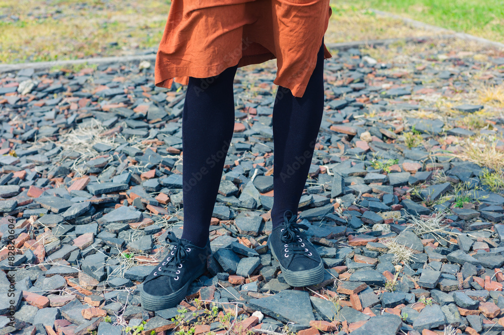 Feet and legs of young woman standing on gravel Feet and legs of young woman standing on gravel