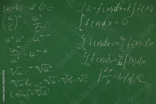 Female hand writing formulas on blackboard with chalk, close up