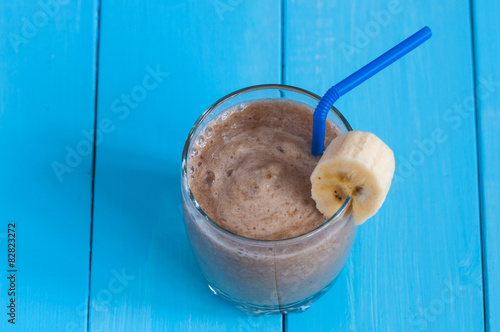 Chocolate milkshake smoothie in glass on blue wooden background.
