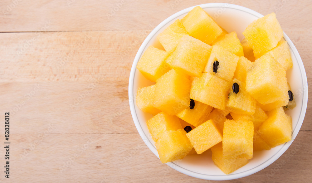 Yellow watermelon fruit in white bowl on wooden cutting board Yellow watermelon fruit in white bowl on wooden cutting board