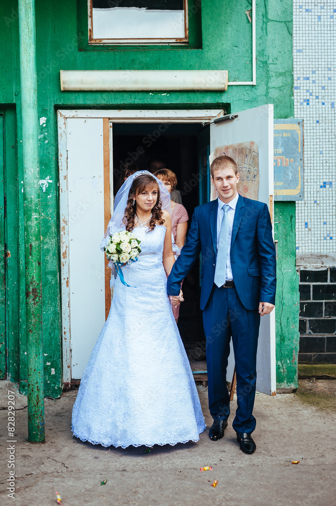Happy bride and groom posing by the old house Happy bride and groom posing by the old house