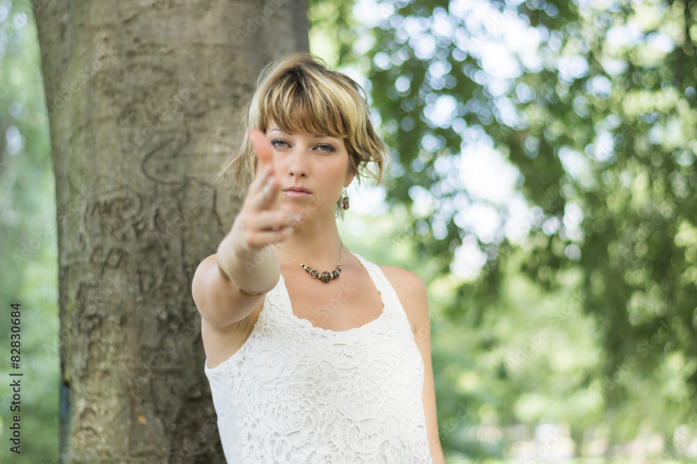 Blonde young woman outdoors pretending to shoot gun with fingers Blonde young woman outdoors pretending to shoot gun with fingers