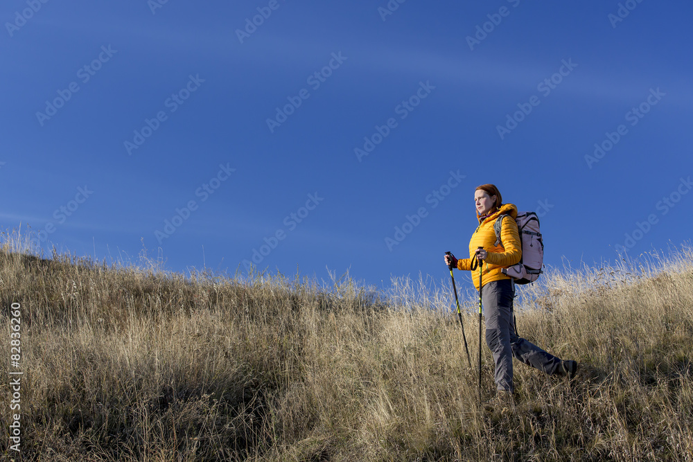 Female hiker walks downhill and enjoys warm sunlight