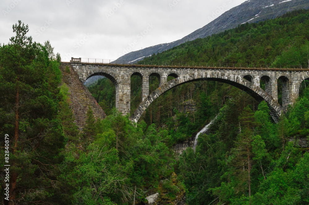 Arch stone bridge in norwegian forest valley