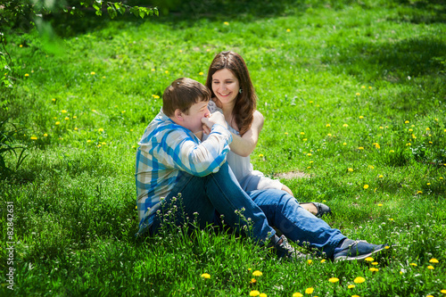 Man with a woman sitting on the grass and he kisses her hand